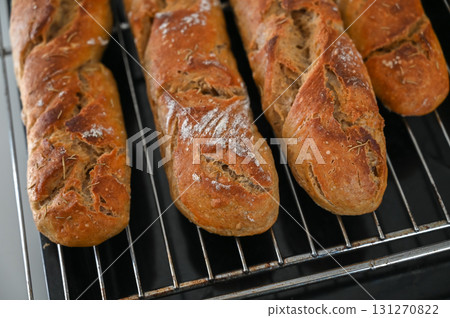 Freshly baked artisanal bread cooling on a rack in a warm and inviting kitchen Freshly baked artisanal bread cooling on a rack in a warm and inviting kitchen 131270822