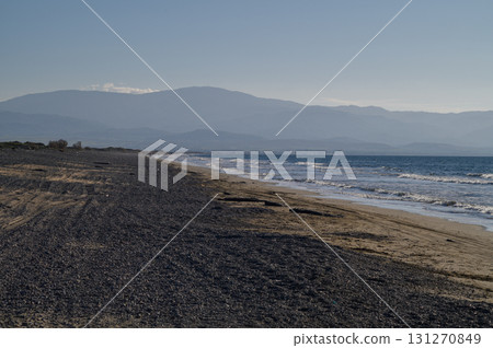 Waves gently lap on a secluded beach with mountains in the distance at twilight 131270849