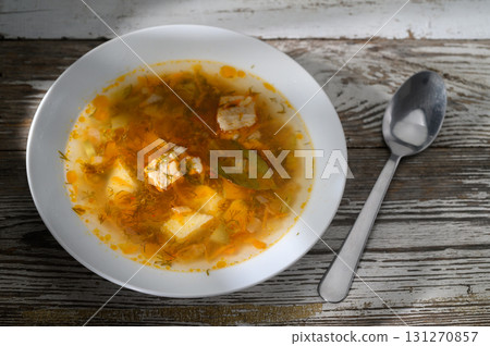 Warm bowl of hearty soup with fresh ingredients resting on rustic wooden table 131270857