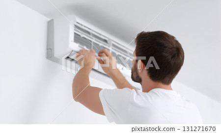 Focused professional male technician carefully cleaning an indoor air conditioner. serviceman providing repair and maintenance service for home appliance system for climate control 131271670