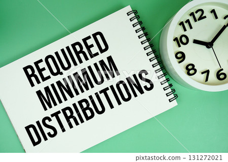 Required Minimum Distribution text with alarm clock flat lay on green background 131272021