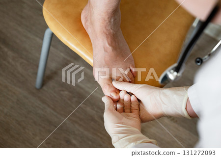 Healthcare professional examines patient's foot in a medical setting during an appointment Healthcare professional examines patient's foot in a medical setting during an appointment 131272093