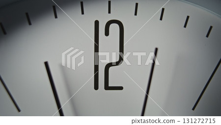 Macro Close Up Shot of Minimalist Wall Clock with Number 12 on Dial, and Running Second and Minute Hands 131272715