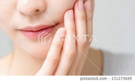 Close-up of a young woman gently touching her face, showcasing smooth skin and natural beauty, with soft lighting creating a serene and calming atmosphere Close-up of a young woman gently touching her face, showcasing smooth skin and natural beauty, with soft lighting creating a serene and calming atmosphere 131273689