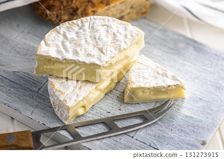 Camembert cheese on cutting board on white table. French cheese with mold on the surface. Camembert cheese on cutting board on white table. French cheese with mold on the surface. 131273915