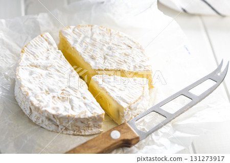 Camembert cheese on wrapping paper. French cheese with mold on the surface. 131273917