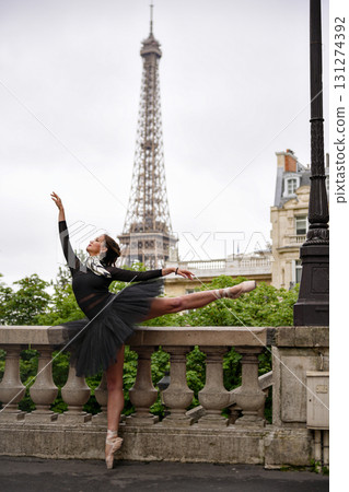 Ballerina in black tutu dancing gracefully near Eiffel Tower in Paris 131274392