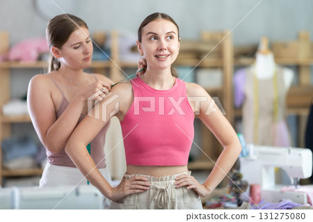 Young dressmaker with measuring tape and takes measurements from a client 131275080