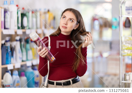 Young woman choosing hairspray in store Young woman choosing hairspray in store 131275081
