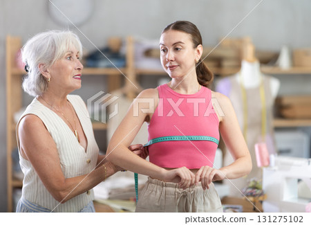 Senior woman tailor measures female client 131275102