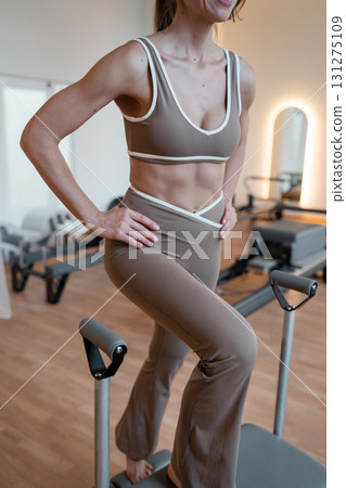 Foot work and core exercise on a Balanced Body Chair machine illuminated by sunlight. Fit, healthy and strong authentical body. Fitness concept 131275109