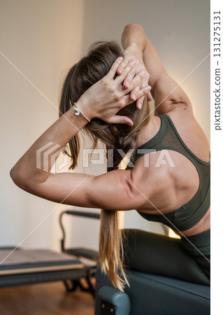 Woman doing Pilates exercise for core and back muscles on Reformer machine with determination and focus on strength body 131275131