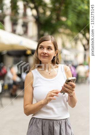 Female pedestrian with phone in summer European capital 131275145
