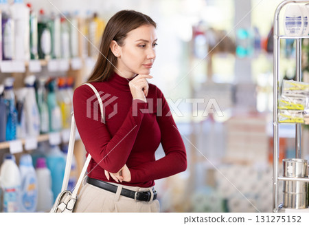 Young woman chooses household chemicals in store Young woman chooses household chemicals in store 131275152