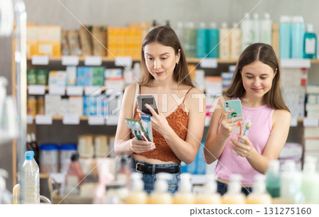 Woman and girl daughter in pharmacy scans QR code on toothbrush kit Woman and girl daughter in pharmacy scans QR code on toothbrush kit 131275160