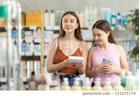 young woman with her daughter choosing pills at the pharmacy 131275174