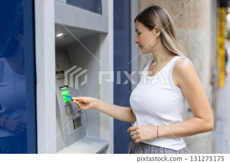 Woman uses outside ATM. Cash withdrawal, user interface 131275175
