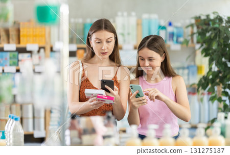 Near display case in pharmacy, mom with daughter scans barcode on paracetamol tablet 131275187