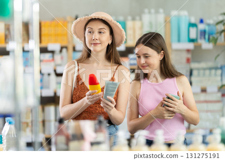Woman with daughter choosing sunscreen in pharmacy 131275191