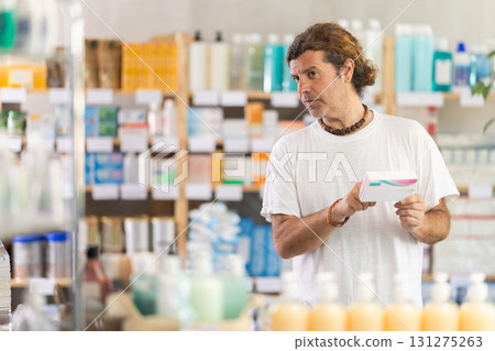adult man chooses a package of pills in a pharmacy adult man chooses a package of pills in a pharmacy 131275263