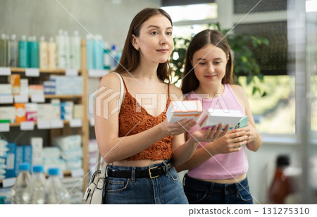 Woman with daughter choosing pills in pharmacy Woman with daughter choosing pills in pharmacy 131275310