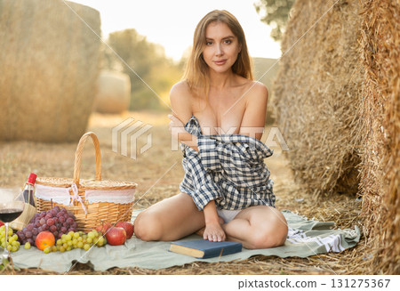Young woman in shirt kneeling during picnic 131275367