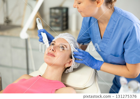 Female cosmetologist performing soften skin keratin and deep clear skin dirt use vibrating shovel leather knife for young female Female cosmetologist performing soften skin keratin and deep clear skin dirt use vibrating shovel leather knife for young female 131275376