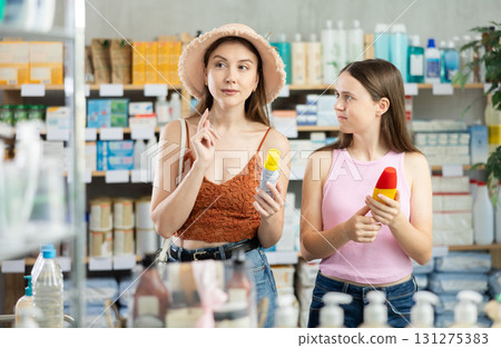 Woman with daughter choosing repellent in pharmacy 131275383