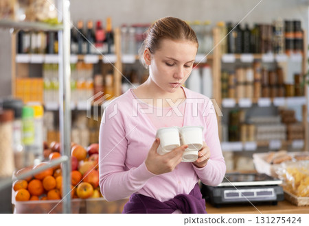 Woman chooses tasty yogurt to buy in the grocery department section of store 131275424