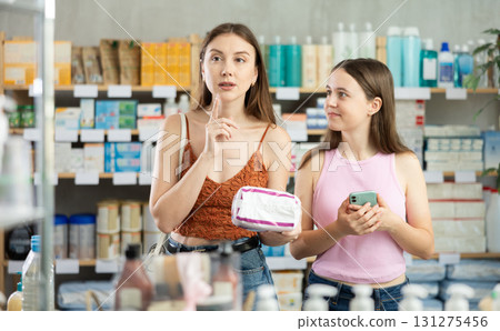 Woman and daughter choosing pads at the pharmacy Woman and daughter choosing pads at the pharmacy 131275456