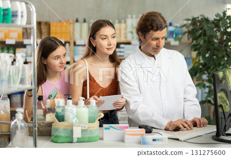 Male pharmacist helps mother and daughter find the right medicine according to prescription at pharmacy Male pharmacist helps mother and daughter find the right medicine according to prescription at pharmacy 131275600