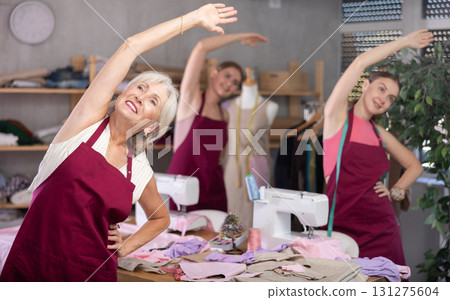 team of dressmakers doing a warm-up in the workshop 131275604