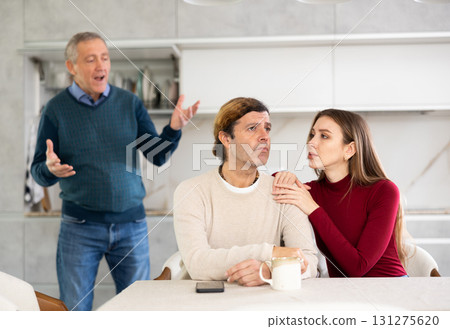 Elderly father scolds and shouts at a married couple. Quarrel in home kitchen Elderly father scolds and shouts at a married couple. Quarrel in home kitchen 131275620