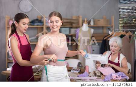 adult female dressmaker takes measurements for a client in the workshop 131275621