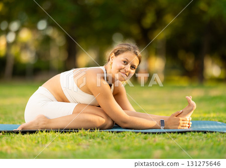 Sporty girl performing yoga asanas on green meadow in summer Sporty girl performing yoga asanas on green meadow in summer 131275646