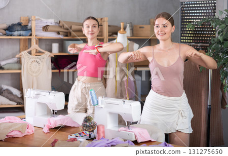 Young and adult women doing warm-up exercises in sewing workshop Young and adult women doing warm-up exercises in sewing workshop 131275650