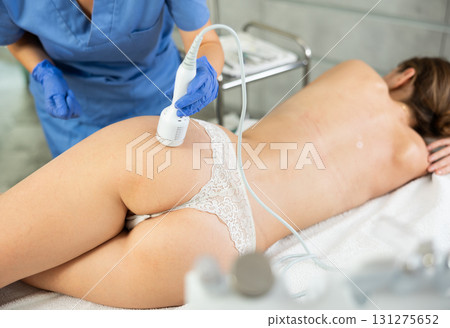 Adult woman cosmetologist performs rejuvenating procedure on butt of young woman Adult woman cosmetologist performs rejuvenating procedure on butt of young woman 131275652