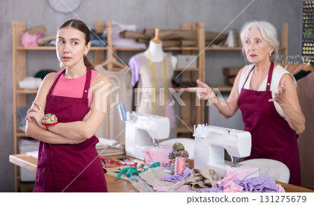 Senior woman head of sewing workshop yells at her subordinate female seamstress, 131275679