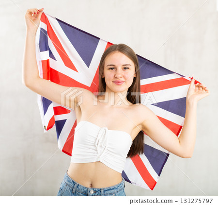 Girl holds unfolded canvas flag of Great Britain in front of her 131275797