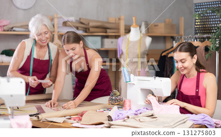 Woman tailor sewing, senior and young employee assistant drawing paper dress pattern by curves Woman tailor sewing, senior and young employee assistant drawing paper dress pattern by curves 131275803