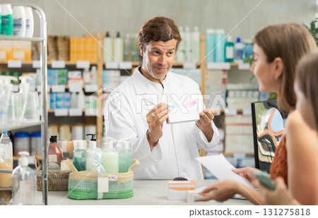 Mother and daughter choose pills in drugstore. Male pharmacist offers to buy pills 131275818