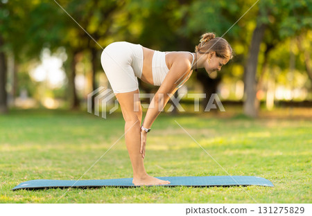 Young woman practicing yoga on green glade in summer park Young woman practicing yoga on green glade in summer park 131275829