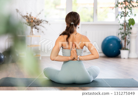 Slender athletic young woman doing stretching and taking various yoga poses in gym Slender athletic young woman doing stretching and taking various yoga poses in gym 131275849