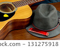 Acoustic Guitar with Felt Hat and Harmonica on a Wooden Table Top Blues Music Concept 131275918