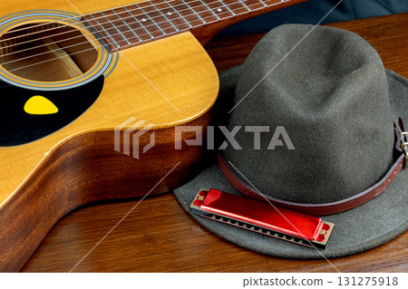 Acoustic Guitar with Felt Hat and Harmonica on a Wooden Table Top Blues Music Concept 131275918