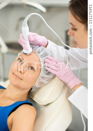 Woman getting face skin massage procedure and moisturize bottom layer of skin in cosmetology clinic. Skin care concept. Beauty treatment 131275951
