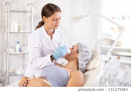 Brunette girl having facial beauty procedure with ice hummer 131275963