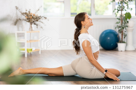 Experienced girl fitness club teacher performs pigeon asana, eka pada rajakapotasana Experienced girl fitness club teacher performs pigeon asana, eka pada rajakapotasana 131275967