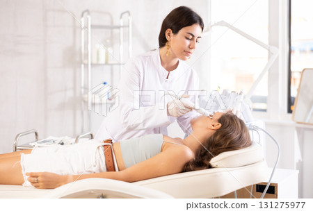 female doctor making facial massage with beauty machine female doctor making facial massage with beauty machine 131275977