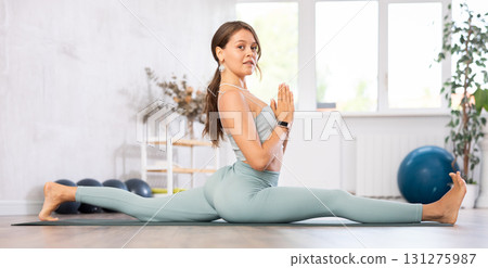 Young athletic woman doing splits while practicing yoga Young athletic woman doing splits while practicing yoga 131275987
